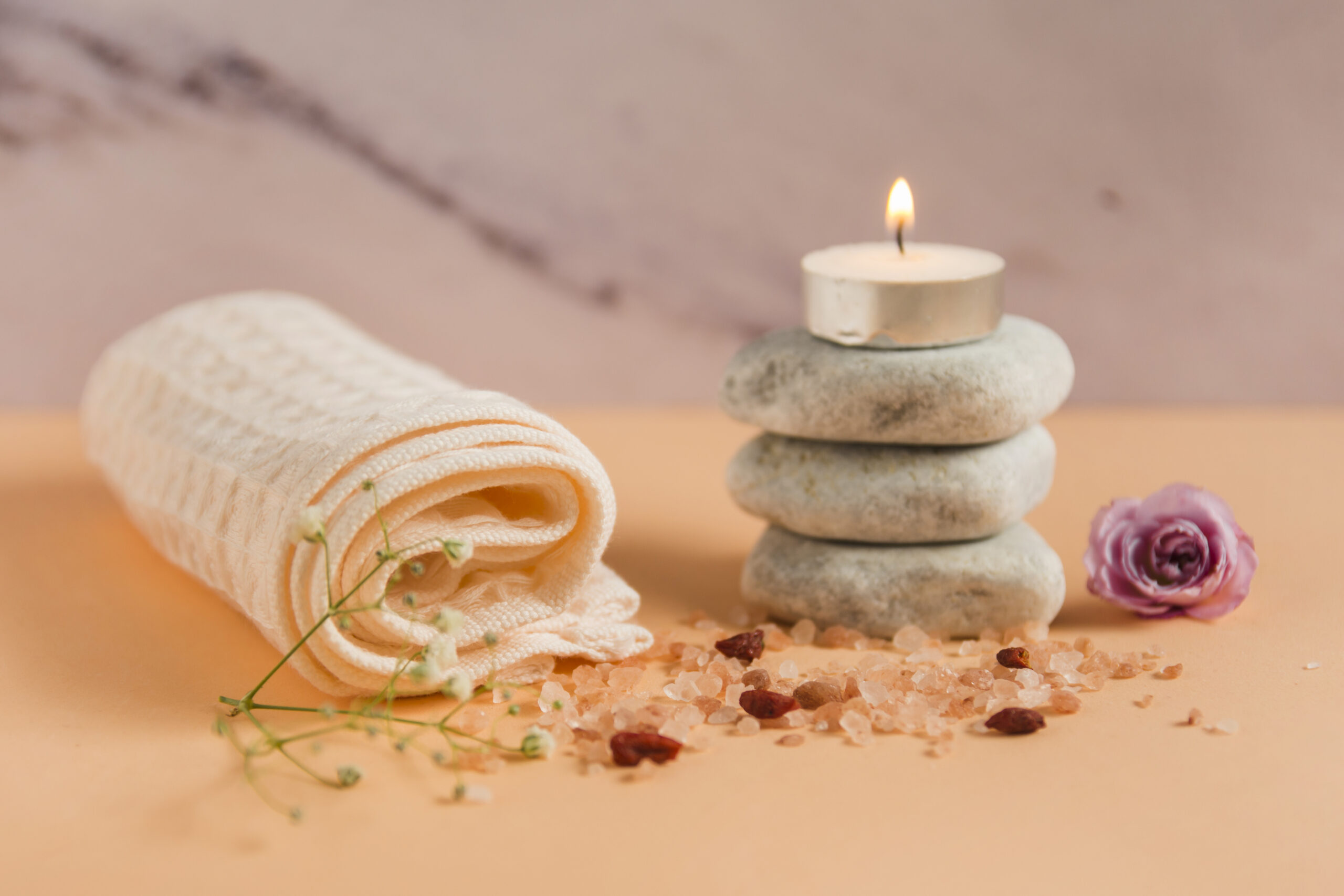 rolled up towel lighted candle spa stones rose himalayan salts peach colored backdrop rolled up towel lighted candle spa stones rose himalayan salts peach colored backdrop